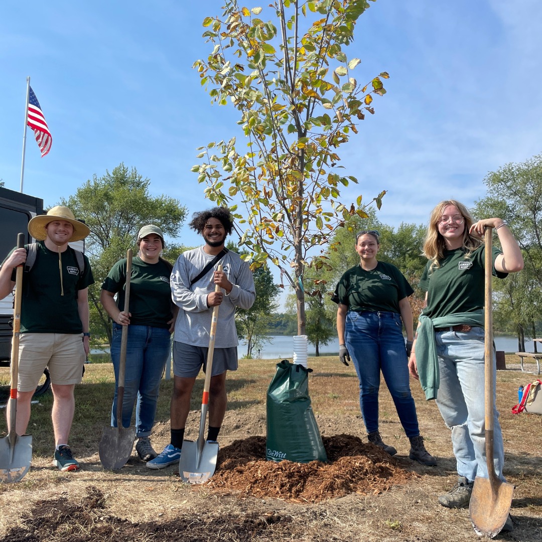 Five members standing around a newly planted tree