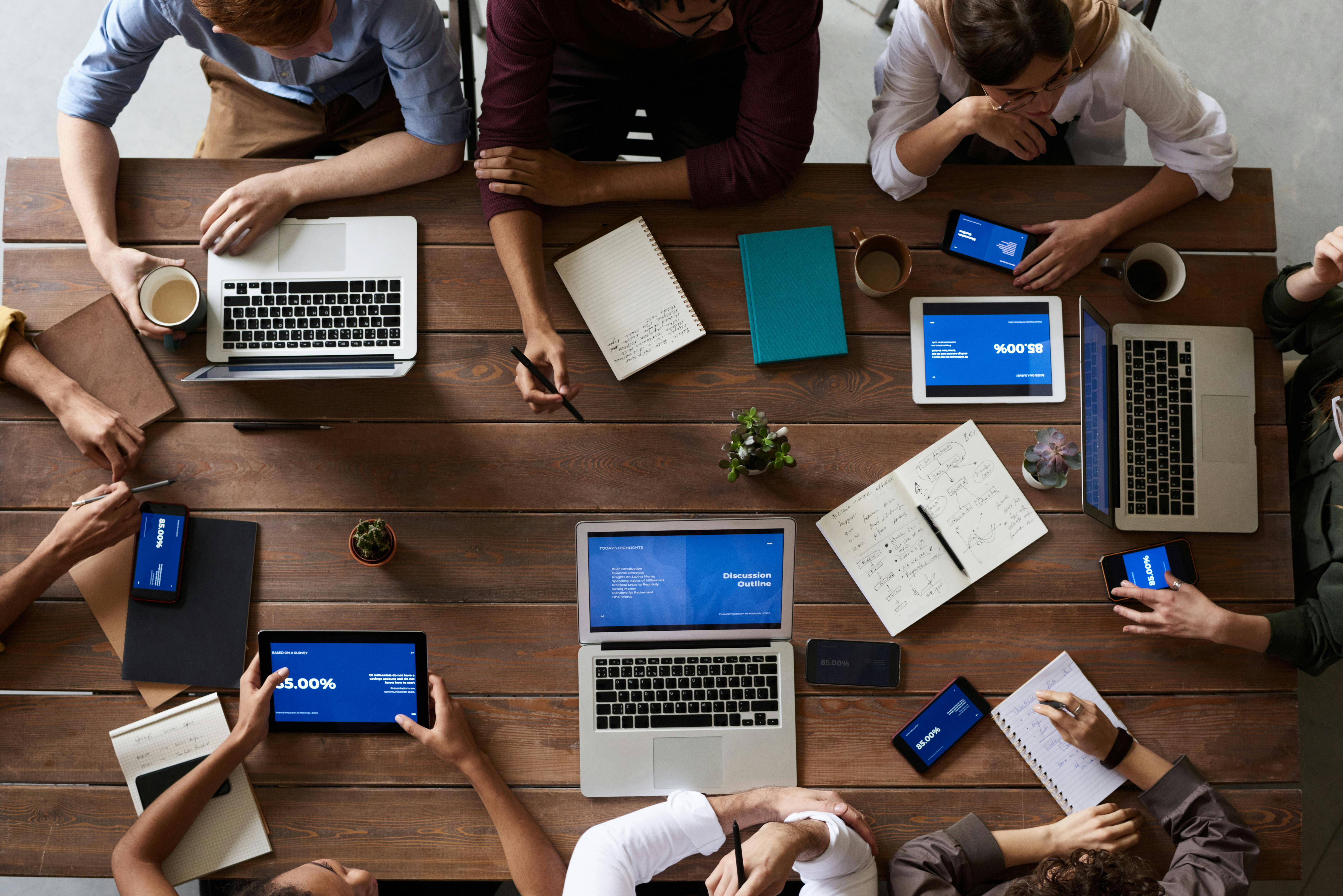 Group of people sitting at a table with laptops and notebooks